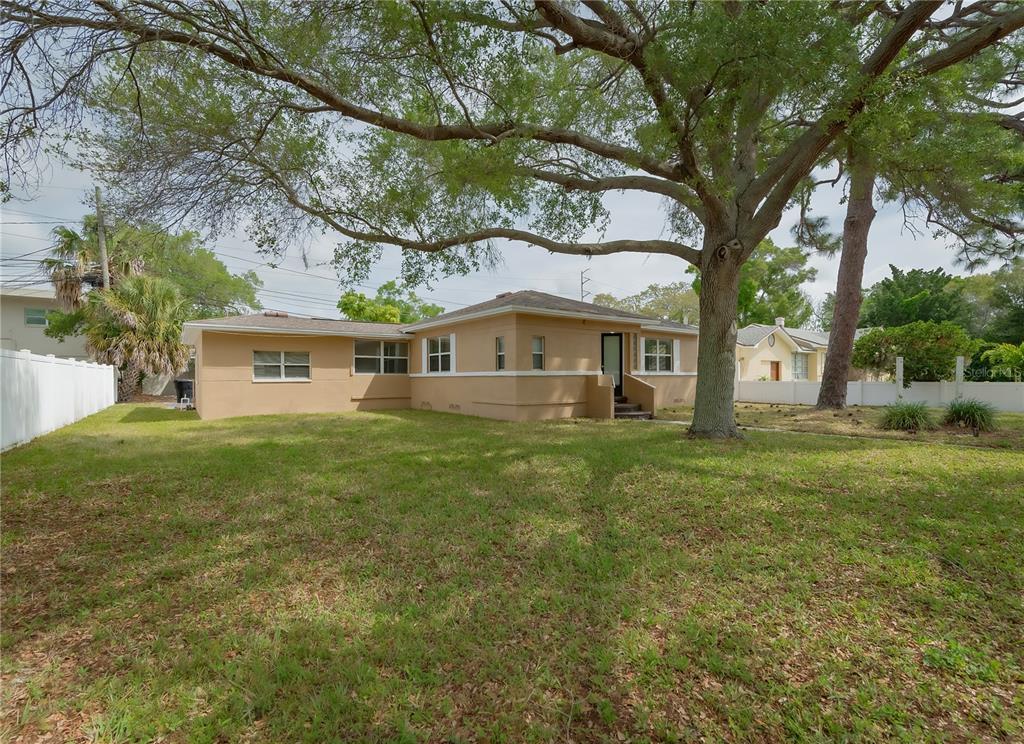A tan, single-story house with a hip roof sits on a grassy lot with trees — 6465 1ST AVENUE S, ST PETERSBURG, FL