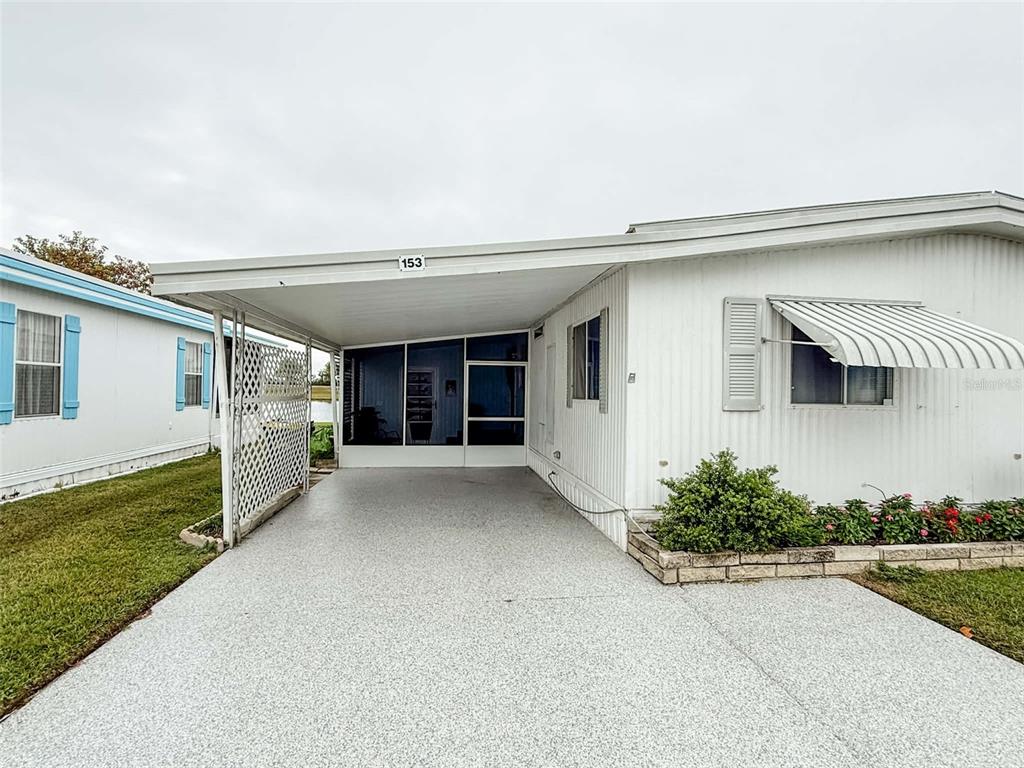 A blue front door with a wreath sits on a porch with wooden steps — 1401 W HIGHWAY 50 UNIT 153, CLERMONT, FL