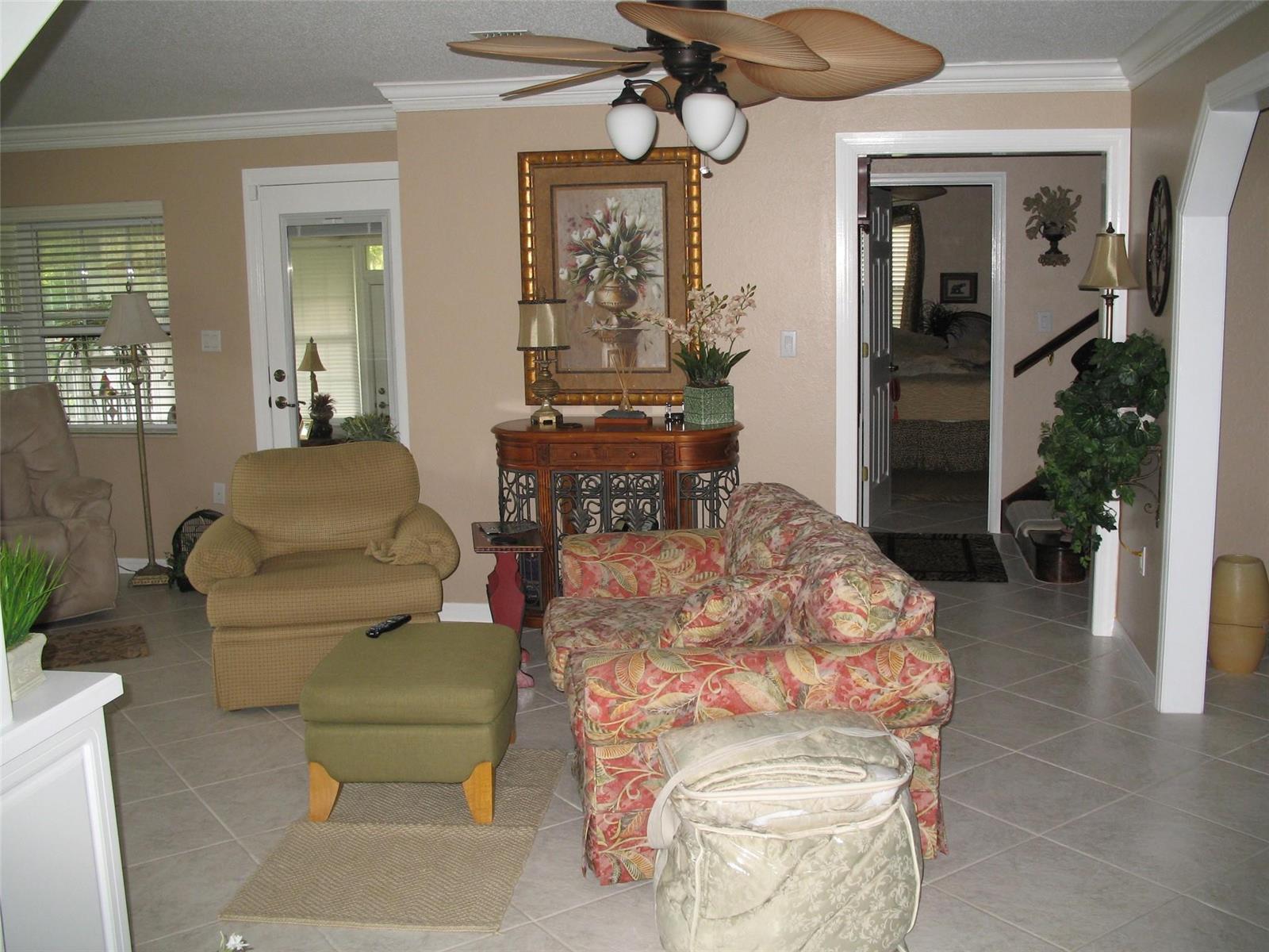 A living room features tile flooring, a patterned loveseat, an armchair, and a ceiling fan — 555 SW 87th Place, Ocala FL 34476, OCALA, FL