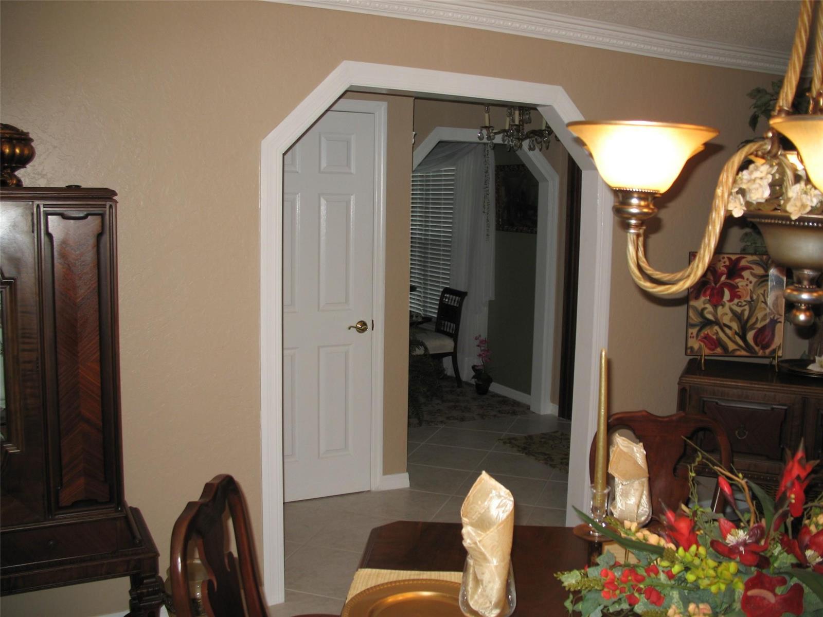 A dining room with a wooden table and chandelier leads through a doorway to another room — 555 SW 87th Place, Ocala FL 34476, OCALA, FL