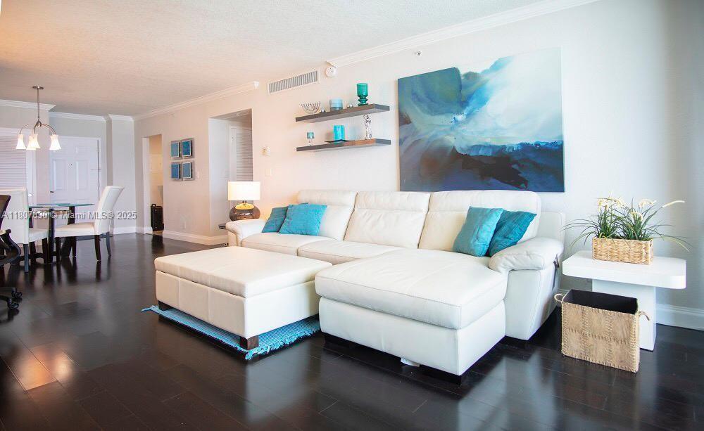 A living room features a white sectional sofa, dark wood floors, and abstract wall art — 2501 S Ocean Dr # 520, Hollywood FL 33019, HOLLYWOOD, FL