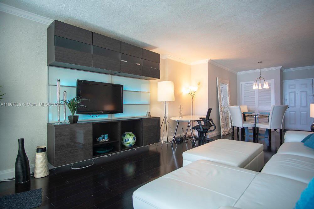 A living room features a dark wood entertainment unit, white sectional sofa, and dining area — 2501 S Ocean Dr # 520, Hollywood FL 33019, HOLLYWOOD, FL
