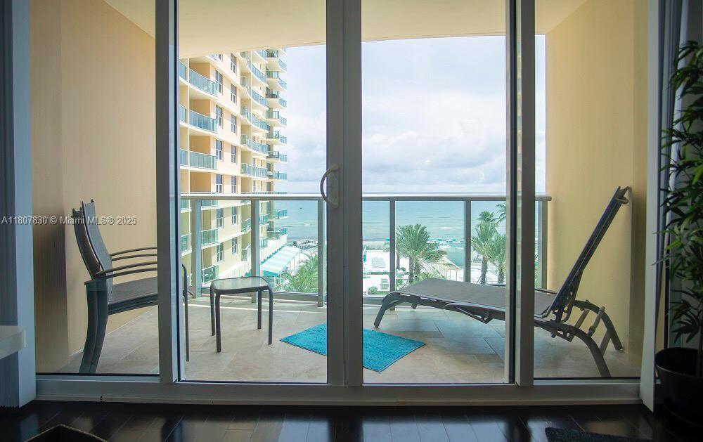 A balcony with a lounge chair and small table overlooks the ocean and nearby buildings — 2501 S Ocean Dr # 520, Hollywood FL 33019, HOLLYWOOD, FL