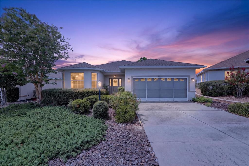 A single-story house with a concrete driveway, a two-car garage, and landscaped front yard — 10055 SW 90TH LOOP, OCALA, FL