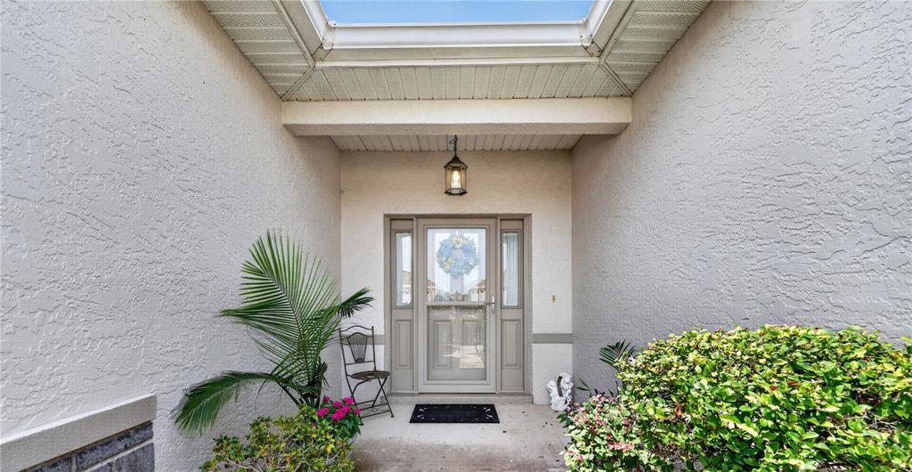 A covered entryway features a front door with sidelights, a skylight, and potted plants — 10055 SW 90TH LOOP, OCALA, FL