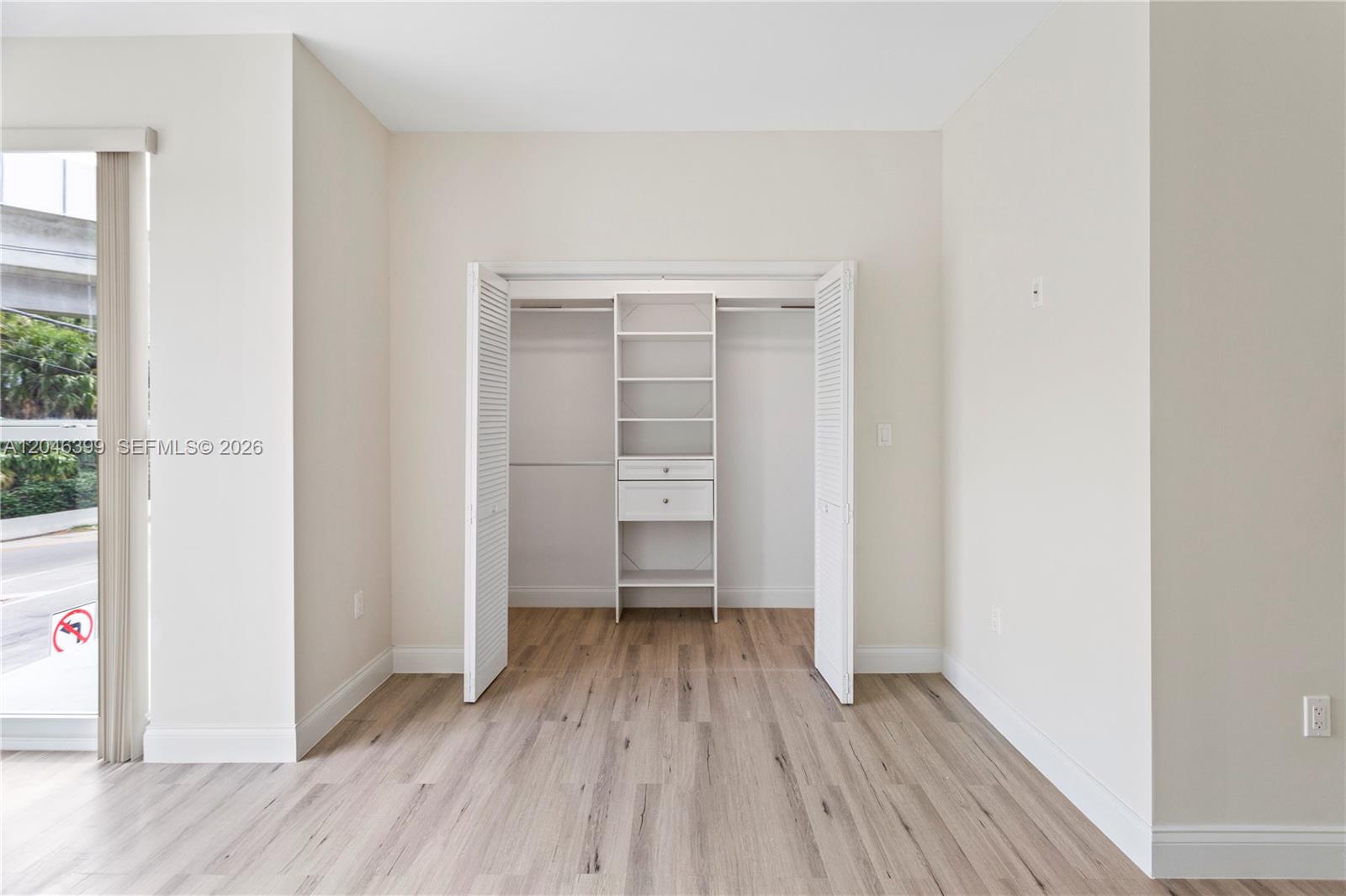 A room with light wood-look flooring features a closet with open shelving and white doors — 1252 NW 39th St # 1252, Miami FL 33142, MIAMI, FL