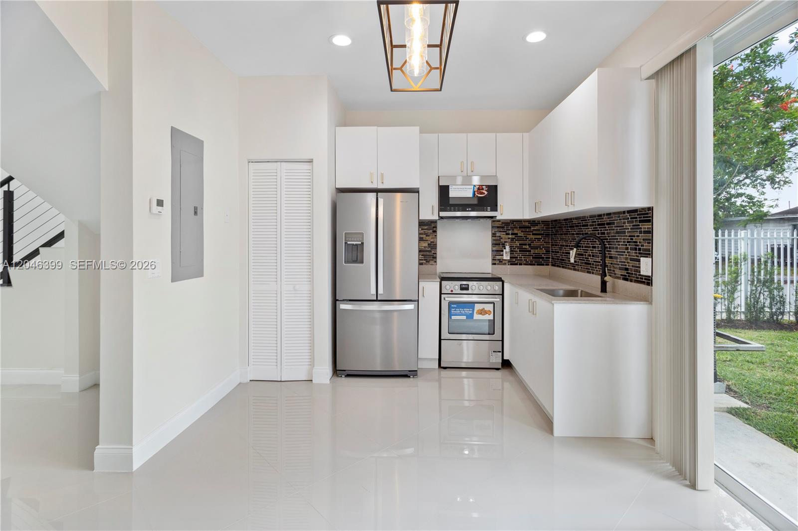 A modern kitchen features white cabinets, stainless steel appliances, and a dark tiled backsplash — 1252 NW 39th St # 1252, Miami FL 33142, MIAMI, FL