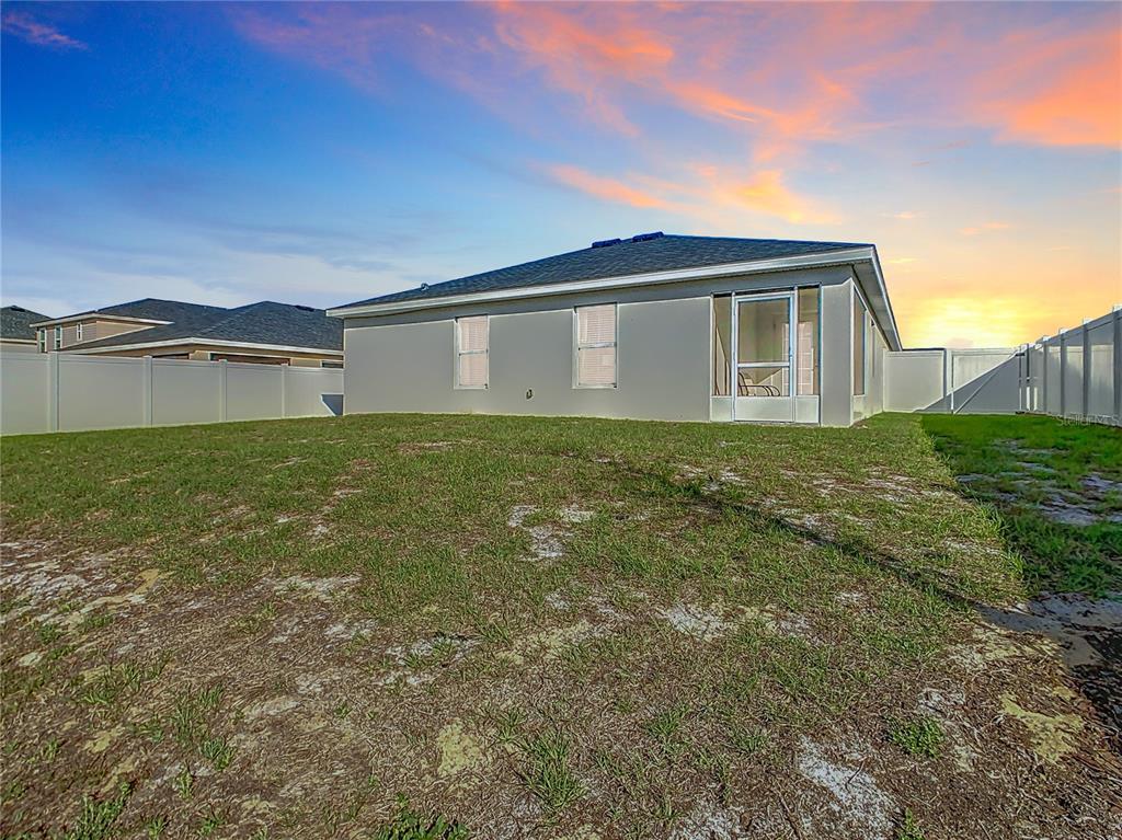 The exterior rear view of a house features a screened-in porch and a fenced yard — 456 HILLTOP DRIVE, LAKE WALES, FL