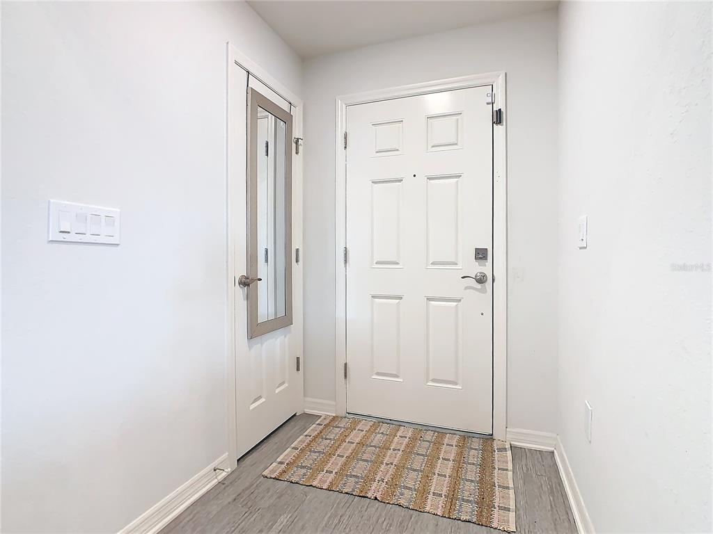 An entryway features a white front door, a closet with a mirrored door, and flooring — 456 HILLTOP DRIVE, LAKE WALES, FL