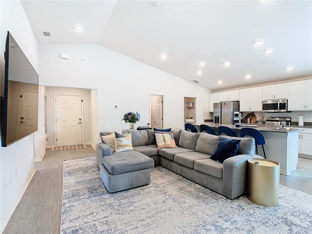 A living room with a gray sectional sofa, area rug, and an open-concept kitchen — 456 HILLTOP DRIVE, LAKE WALES, FL