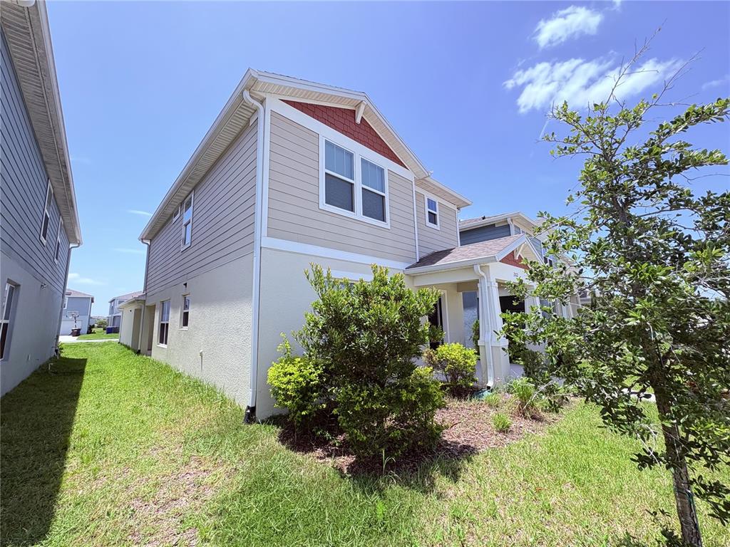 A two-story house with beige siding and stucco exterior stands on a grassy lot — 2012 CROSS PRAIRIE PARKWAY, KISSIMMEE, FL