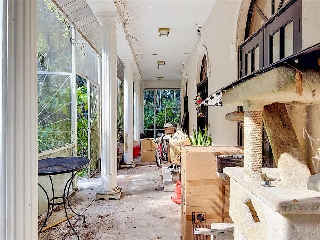 A covered porch features white columns, a concrete floor, and various boxes and furniture — 7350 PALOMINO TRAIL, SARASOTA, FL