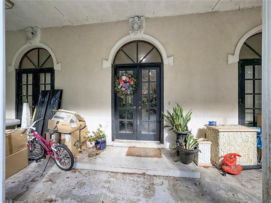 A covered porch features a double glass door with a wreath and arched windows — 7350 PALOMINO TRAIL, SARASOTA, FL
