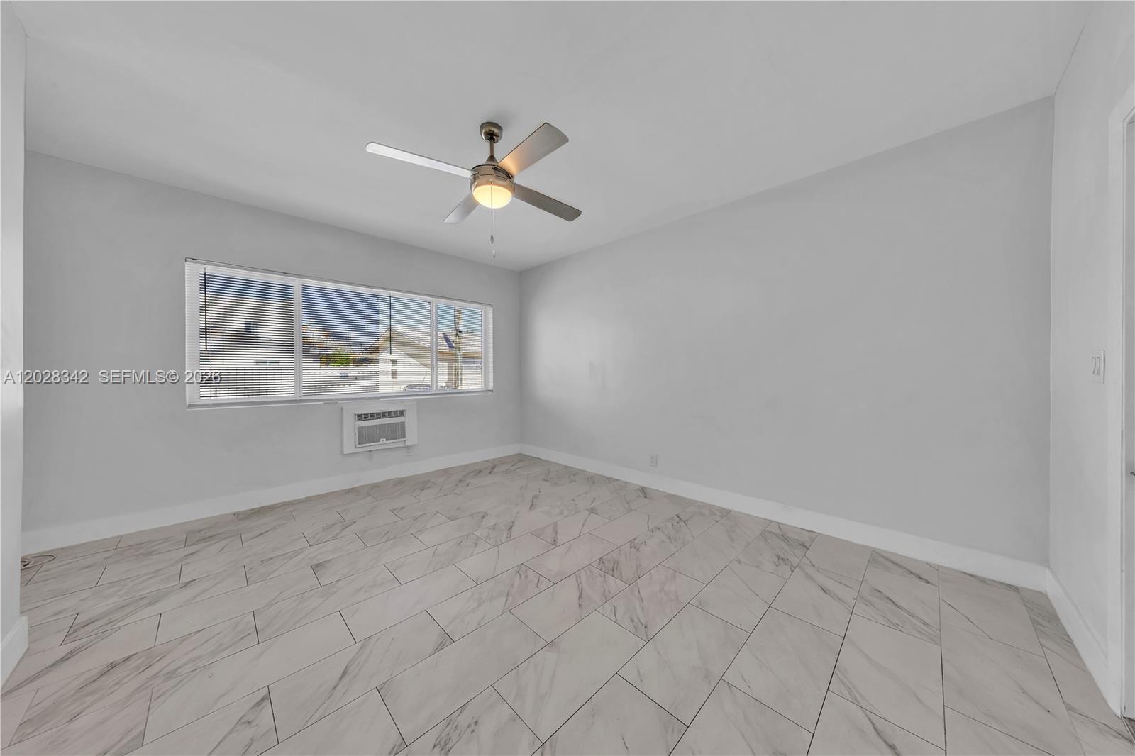 An empty bedroom features light gray walls, white tile flooring, and a ceiling fan — 1839 Funston St # 4, Hollywood FL 33020, HOLLYWOOD, FL