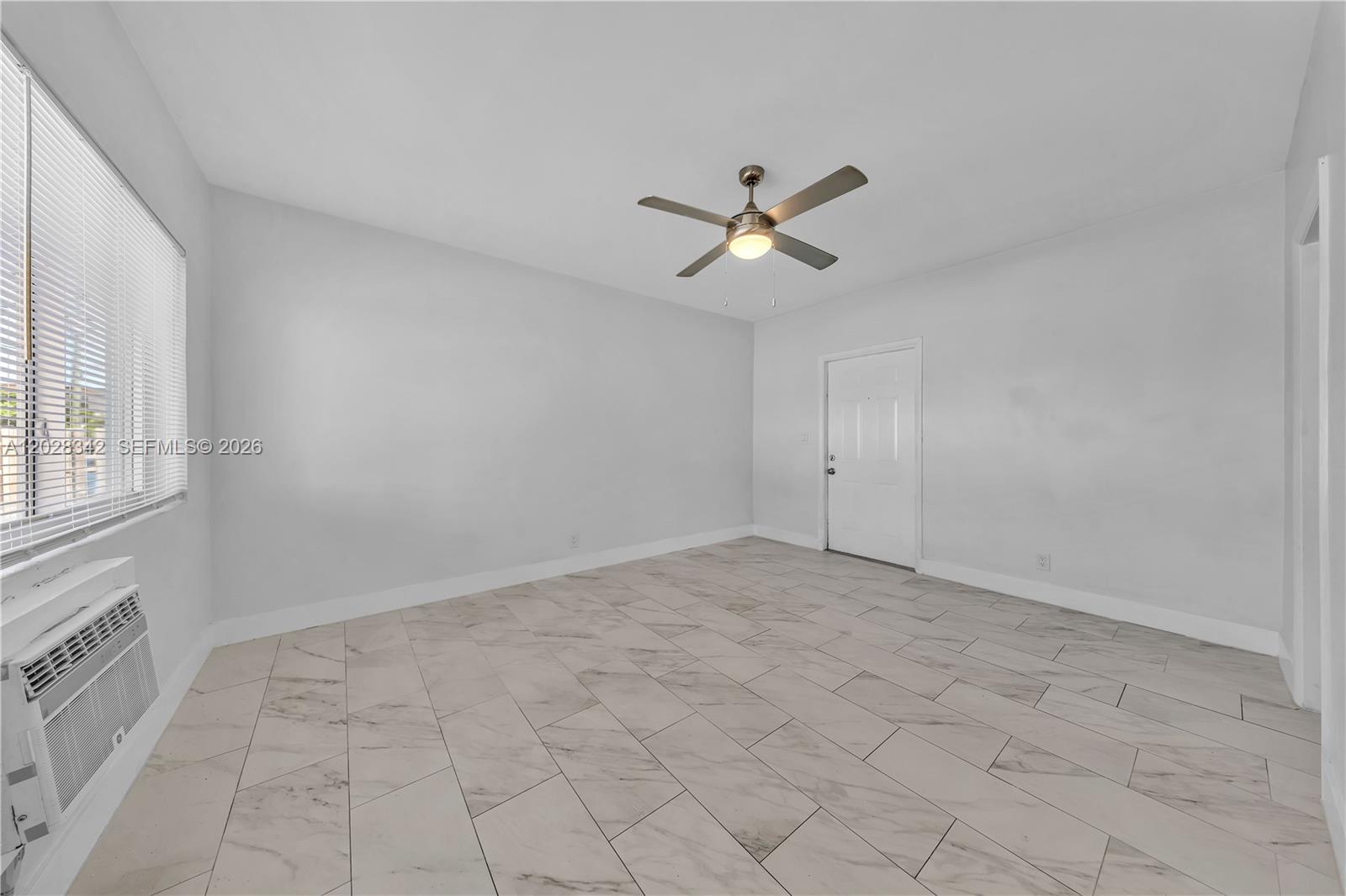 An empty room features white walls, a ceiling fan, and light-colored marble-look tile flooring — 1839 Funston St # 4, Hollywood FL 33020, HOLLYWOOD, FL