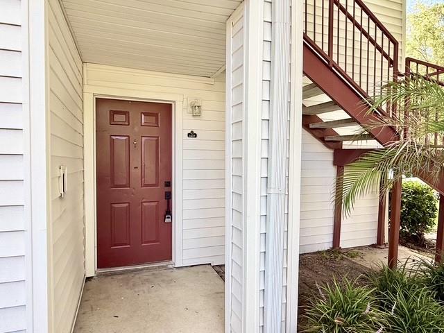 A red front door is situated next to a white staircase on a building exterior — 11594 WESTWOOD BOULEVARD UNIT 1617, ORLANDO, FL