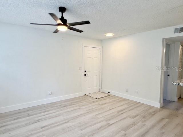 An empty room features light wood-look flooring, a ceiling fan, and a white entry door — 11594 WESTWOOD BOULEVARD UNIT 1617, ORLANDO, FL