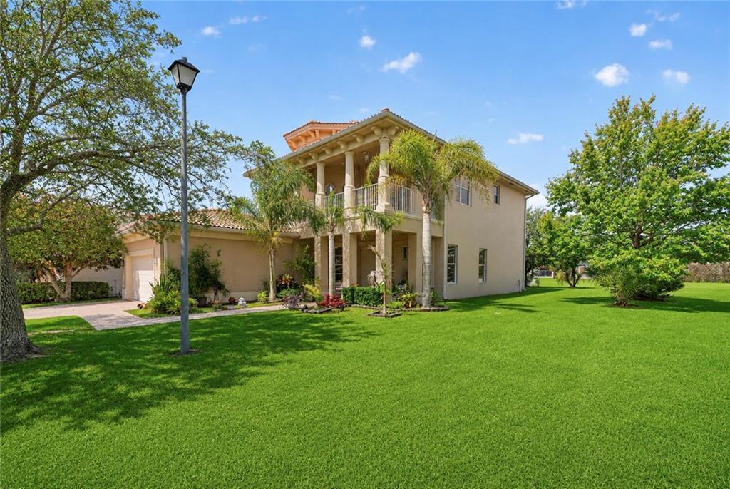 A two-story stucco house with a columned balcony stands on a large, grassy lawn — VERO BEACH, FL