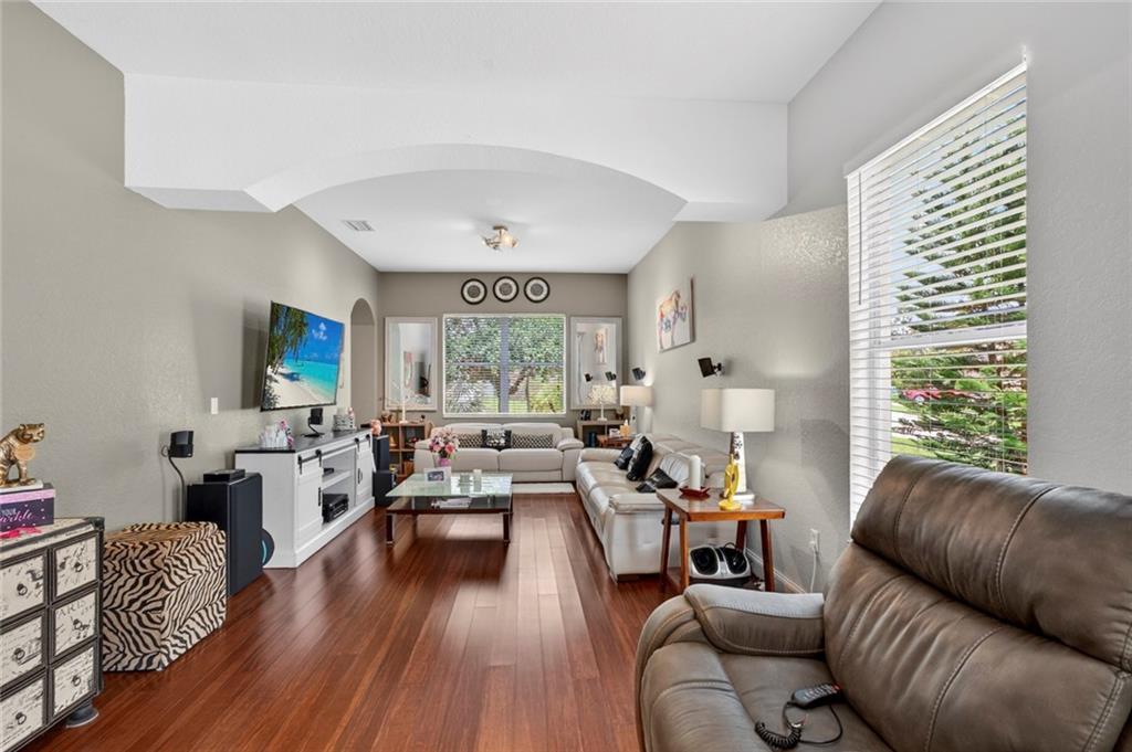 A living room features hardwood floors, a white media console, and two white leather sofas — VERO BEACH, FL