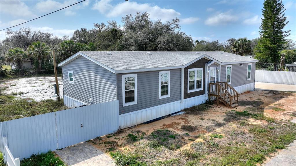 An exterior view of a gray manufactured home with a wooden porch and metal fencing — 2337 E MAIN STREET, LAKELAND, FL