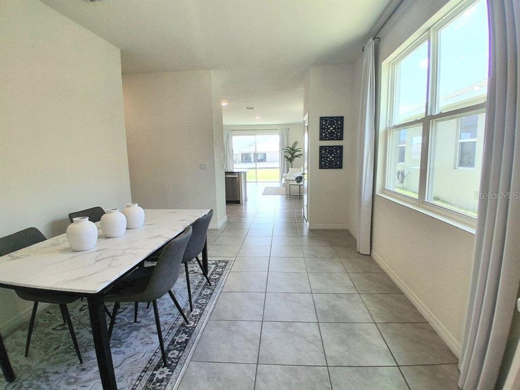 A dining area with a marble-topped table leads into a kitchen and living space — 8072 PENROSE PLACE, WILDWOOD, FL
