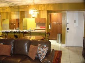 A living room with a brown leather sofa, dining area, and kitchen cabinets — 900 NE 209th Ter # 31, Miami FL 33179, MIAMI, FL