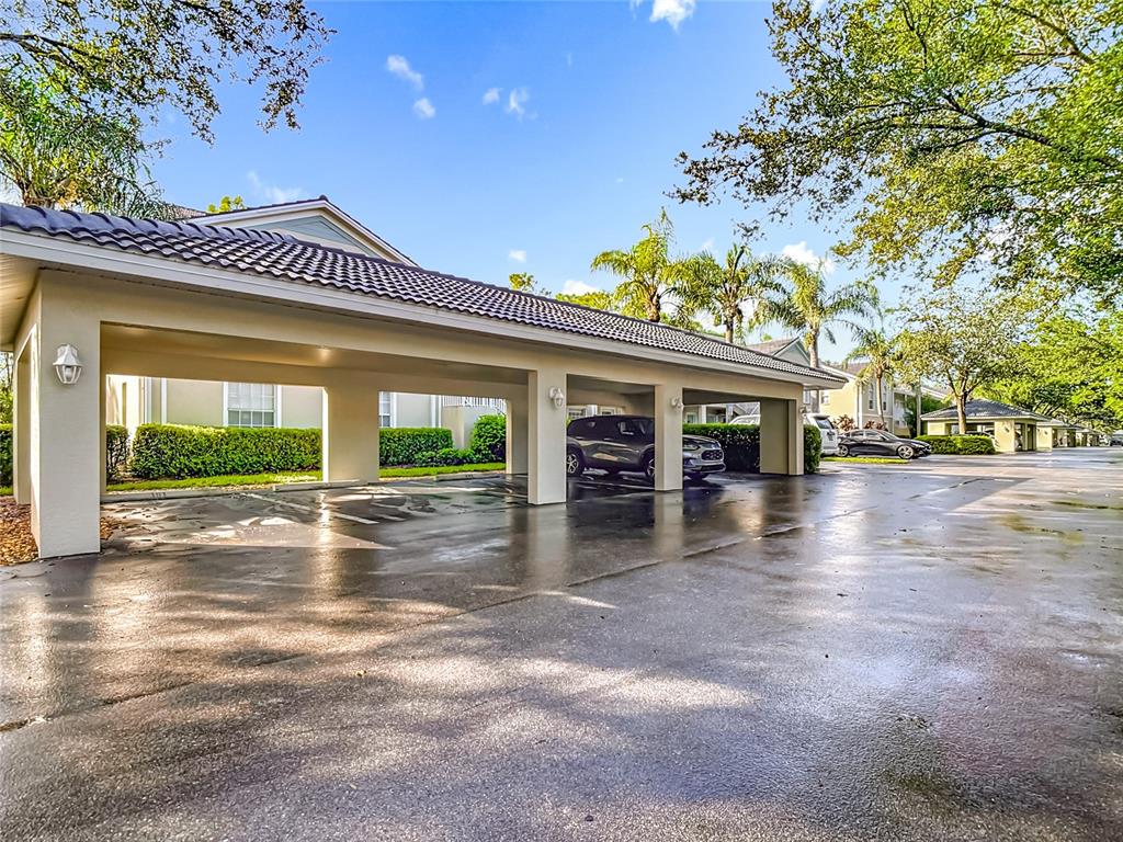 A covered parking structure with multiple bays sits in front of a residential building — 25735 LAKE AMELIA WAY UNIT 103, BONITA SPRINGS, FL