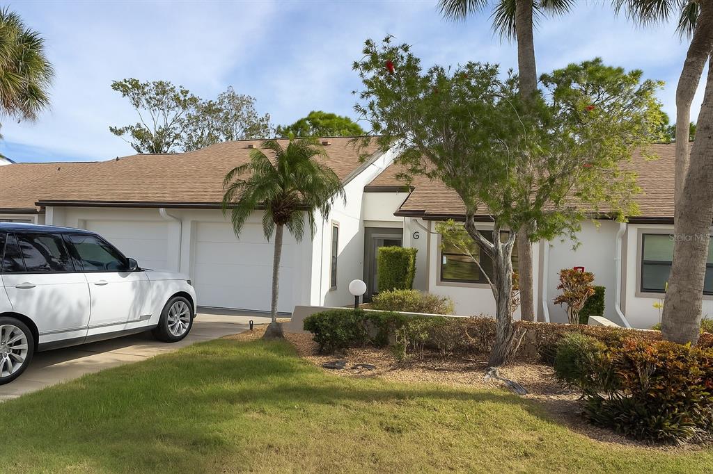 A white single-story house with a two-car garage and a palm tree in front — 1211 CAPRI ISLES BOULEVARD UNIT 6, VENICE, FL
