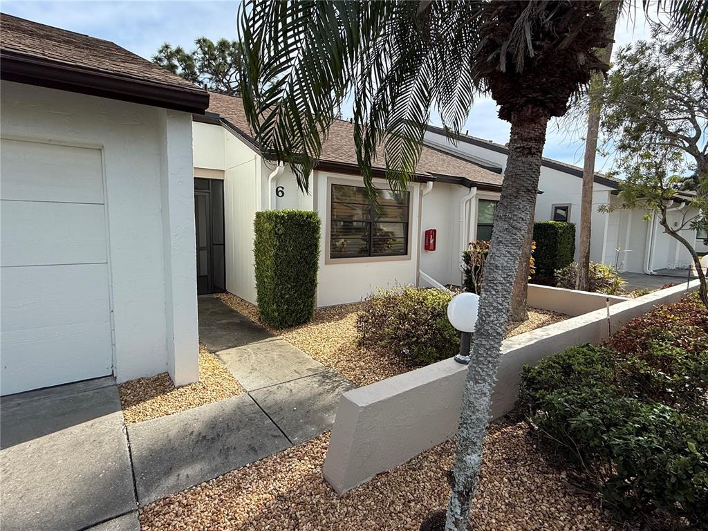 A single-story residential unit with a white exterior, a garage, and a landscaped front yard — 1211 CAPRI ISLES BOULEVARD UNIT 6, VENICE, FL