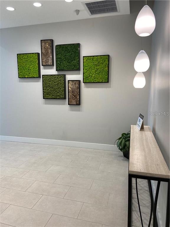 A modern entryway features a tiled floor, a console table, and wall-mounted moss art pieces — 1500 STATE STREET UNIT 401, SARASOTA, FL