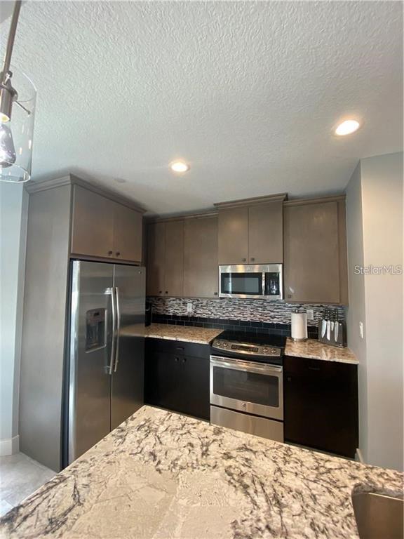 A kitchen features dark brown cabinets, stainless steel appliances, and a granite-topped island — 1500 STATE STREET UNIT 401, SARASOTA, FL