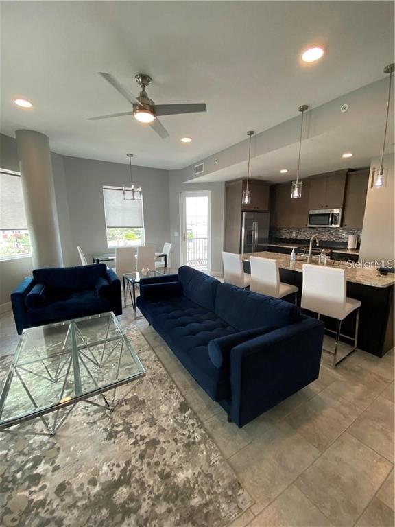 An open-concept living room and kitchen feature a blue sofa, glass coffee table, and island — 1500 STATE STREET UNIT 401, SARASOTA, FL