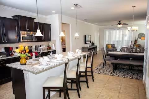 A kitchen with dark cabinets and a granite island opens into a dining and living area — 8956 RHODES STREET, KISSIMMEE, FL