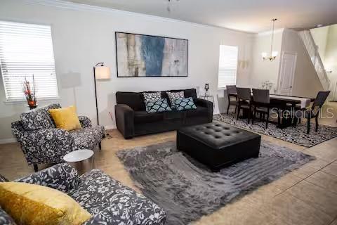 A living room features a dark sofa, patterned armchairs, a black ottoman, and a dining area — 8956 RHODES STREET, KISSIMMEE, FL