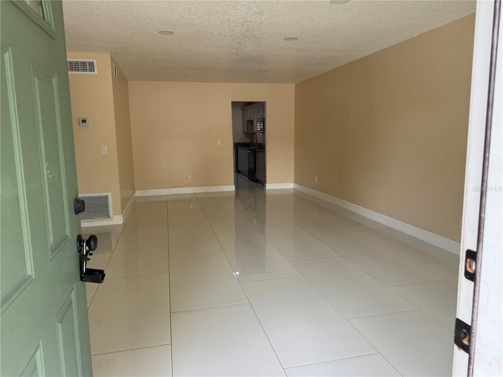 An interior view shows a living area with large white floor tiles and beige walls — 725 NORTHLAKE BOULEVARD UNIT 18, ALTAMONTE SPRINGS, FL