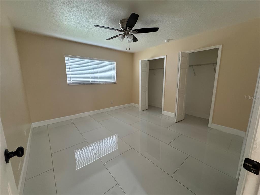 A bedroom features light-colored walls, a ceiling fan, two open closets, and large white tiles — 725 NORTHLAKE BOULEVARD UNIT 18, ALTAMONTE SPRINGS, FL