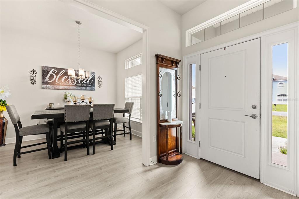 A dining area with a wooden table and chairs sits beside a white front door — 1234 NELSON PARK CT, POINCIANA, FL