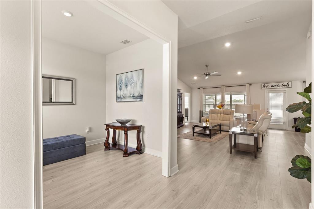 A bright entryway with light wood-look flooring leads into an open-concept living room — 1234 NELSON PARK CT, POINCIANA, FL