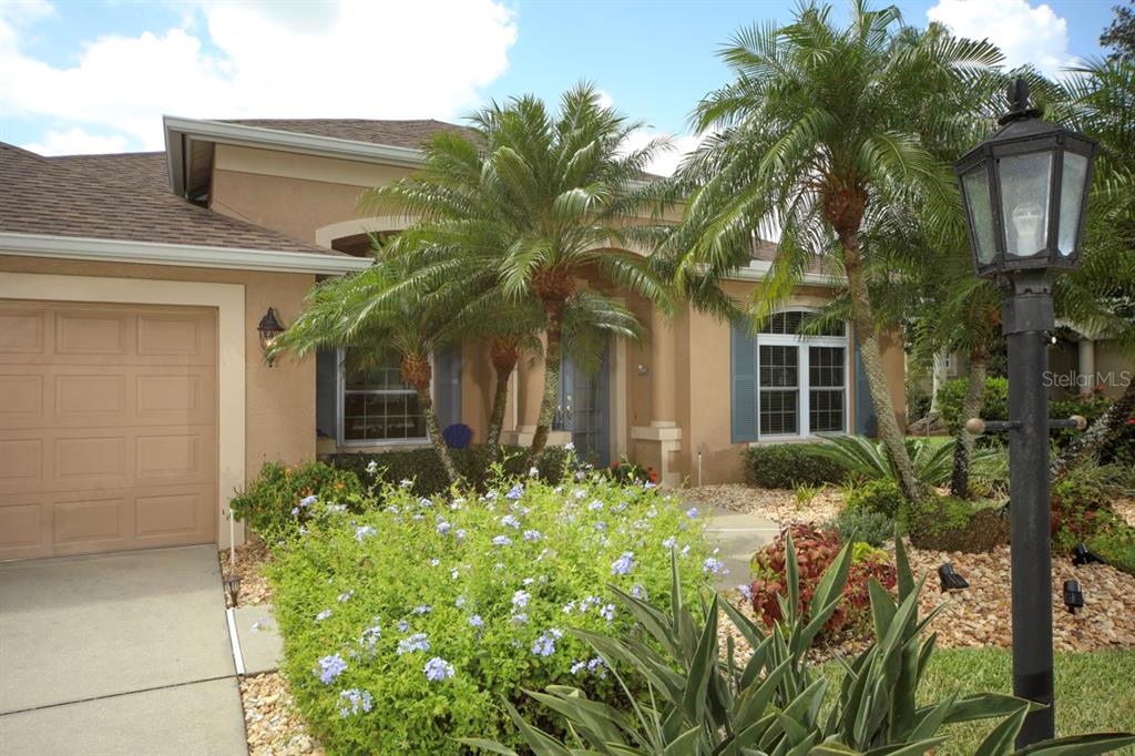The exterior of a tan stucco house features a garage, palm trees, and landscaping — 11914 SOFT RUSH TERRACE, LAKEWOOD RANCH, FL