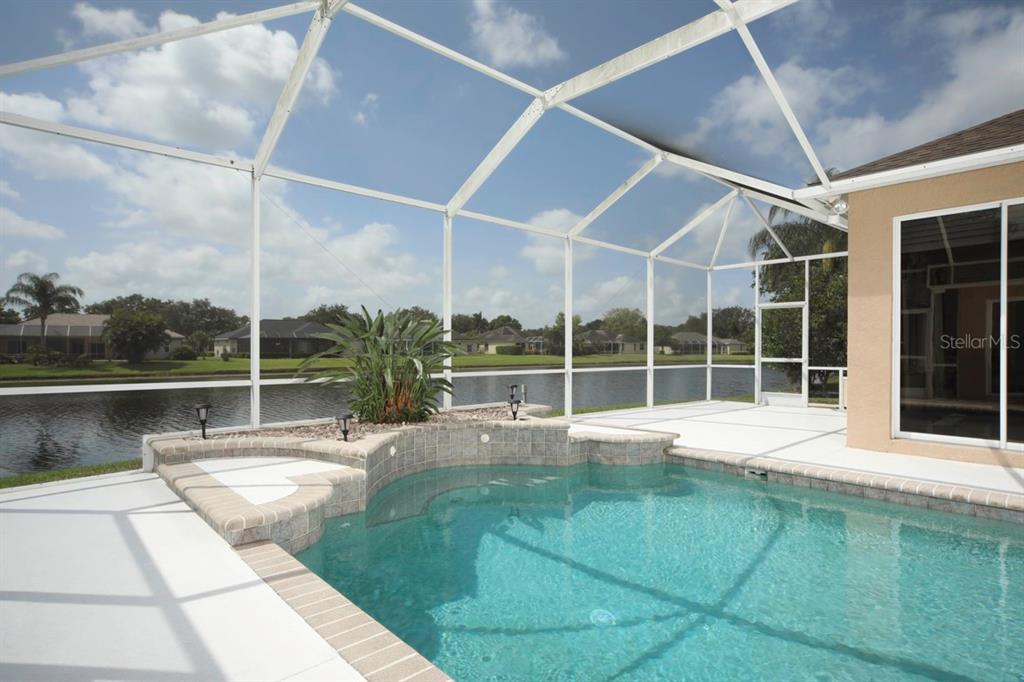 A screened-in pool and spa area overlooks a lake behind a residential home — 11914 SOFT RUSH TERRACE, LAKEWOOD RANCH, FL