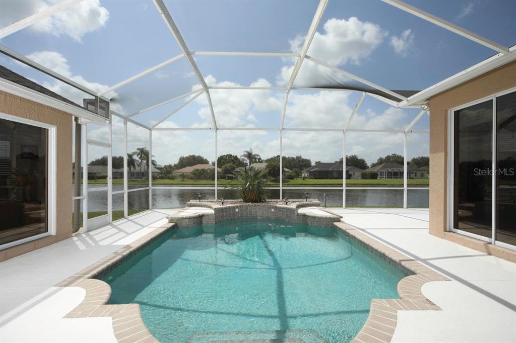 A screened-in pool patio overlooks a lake with a raised spa and tiled deck — 11914 SOFT RUSH TERRACE, LAKEWOOD RANCH, FL