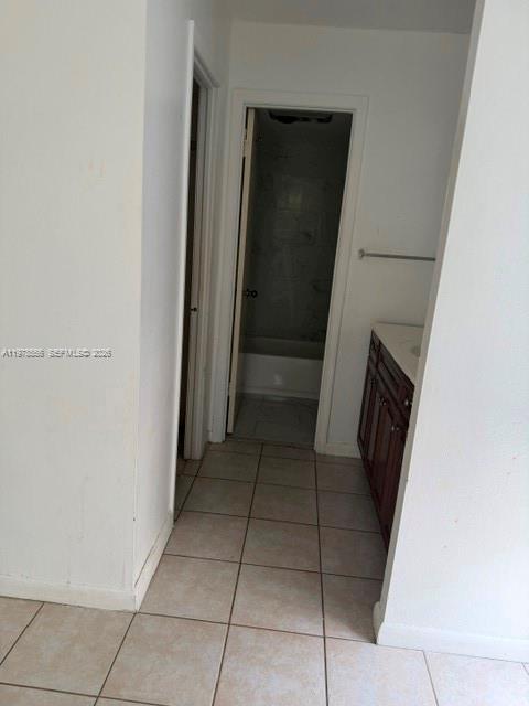 A tiled hallway leads to a bathroom featuring a vanity and a shower-tub combination — 7031 Environ Blvd # 221, Lauderhill FL 33319, LAUDERHILL, FL