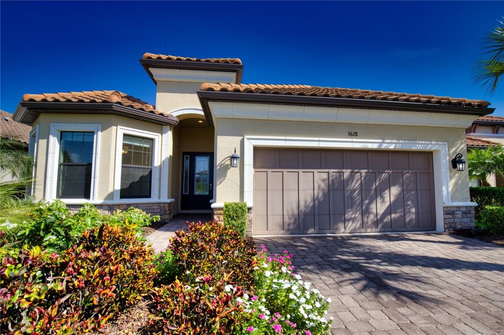 A single-story house with a tan stucco exterior, tile roof, and a two-car garage — 5628 SEMOLINO STREET, NOKOMIS, FL