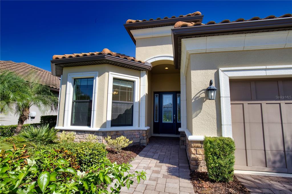 The exterior of a house features a stone-accented facade, a paved walkway, and a garage — 5628 SEMOLINO STREET, NOKOMIS, FL