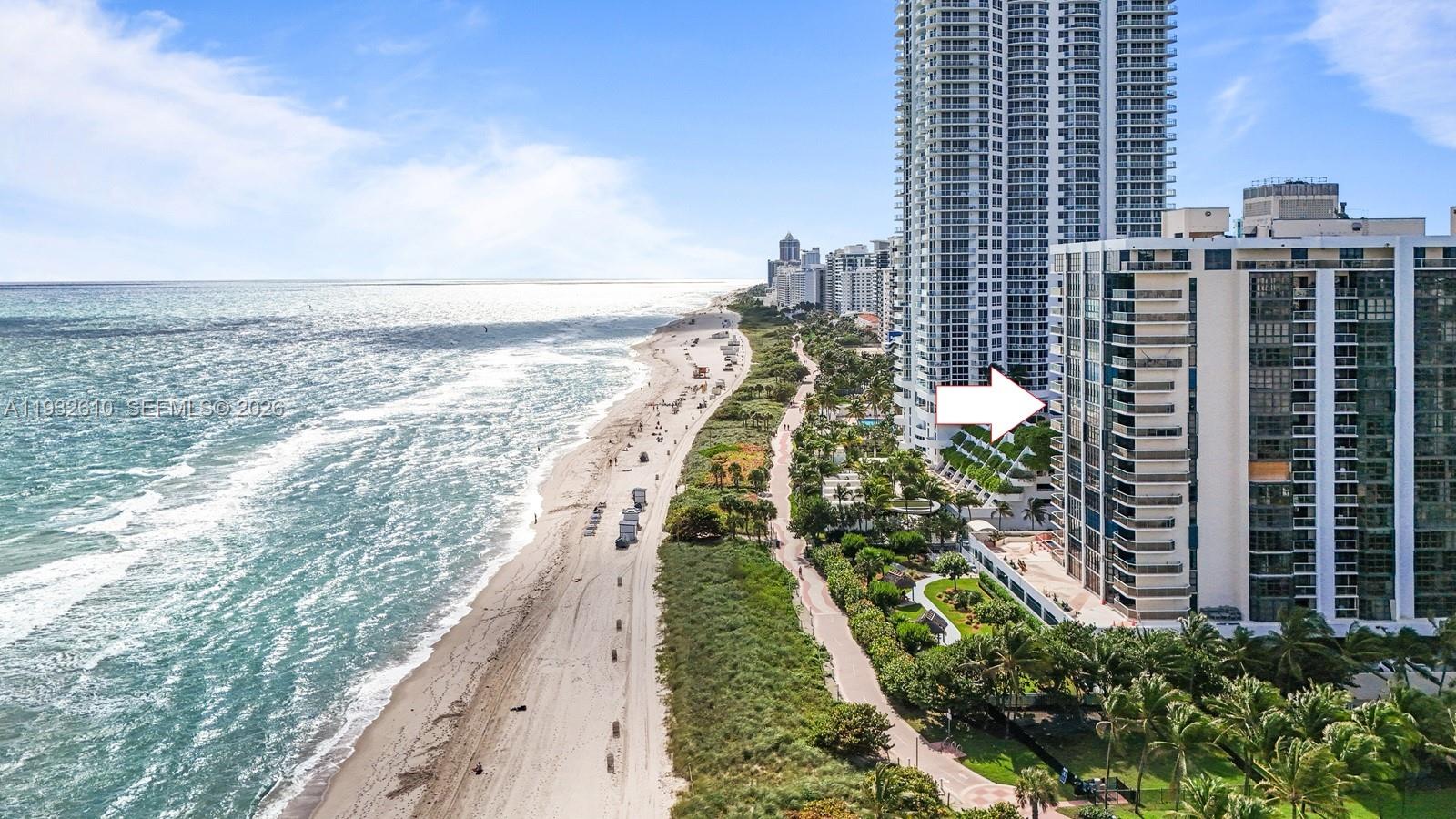 An aerial view shows a high-rise residential building situated along a sandy beach — 6423 Collins Ave # 1005, Miami Beach FL 33141, MIAMI BEACH, FL