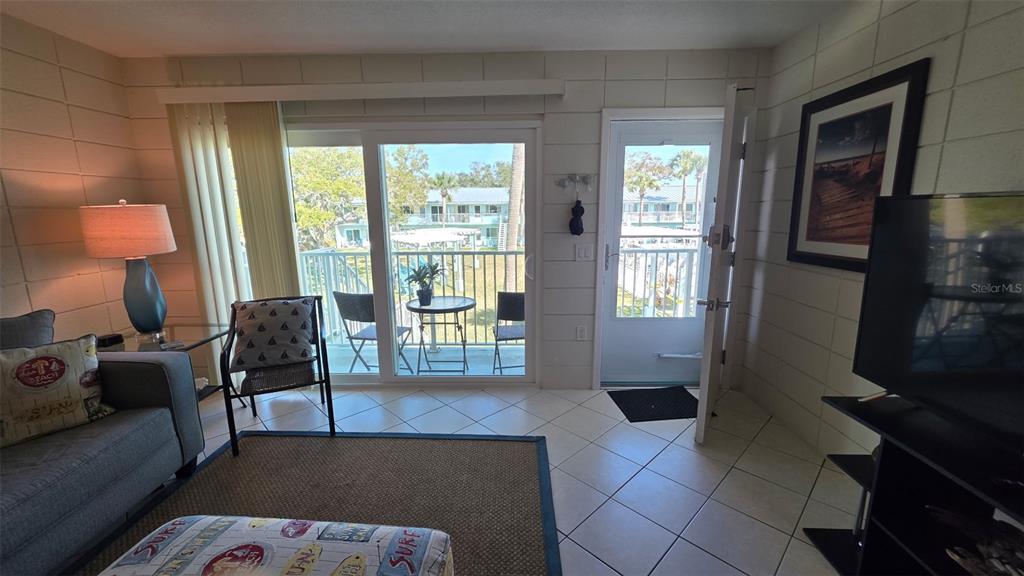A living room features tile floors, a sliding glass door, and a view of balconies — 541 S PENINSULA AVENUE UNIT A21, NEW SMYRNA BEACH, FL