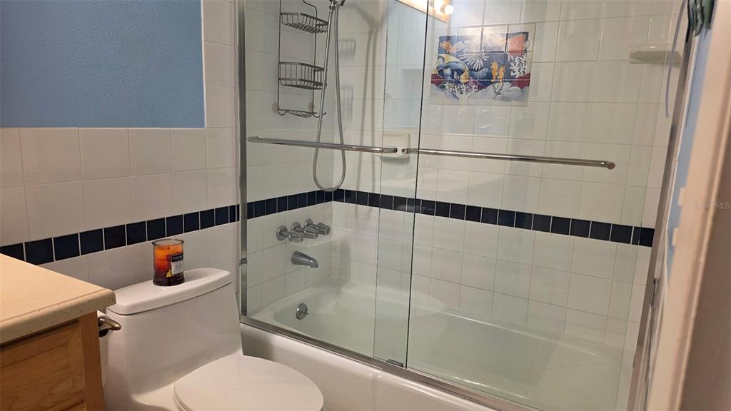 A bathroom features a white toilet, a bathtub with a shower, and tiled walls — 541 S PENINSULA AVENUE UNIT A21, NEW SMYRNA BEACH, FL