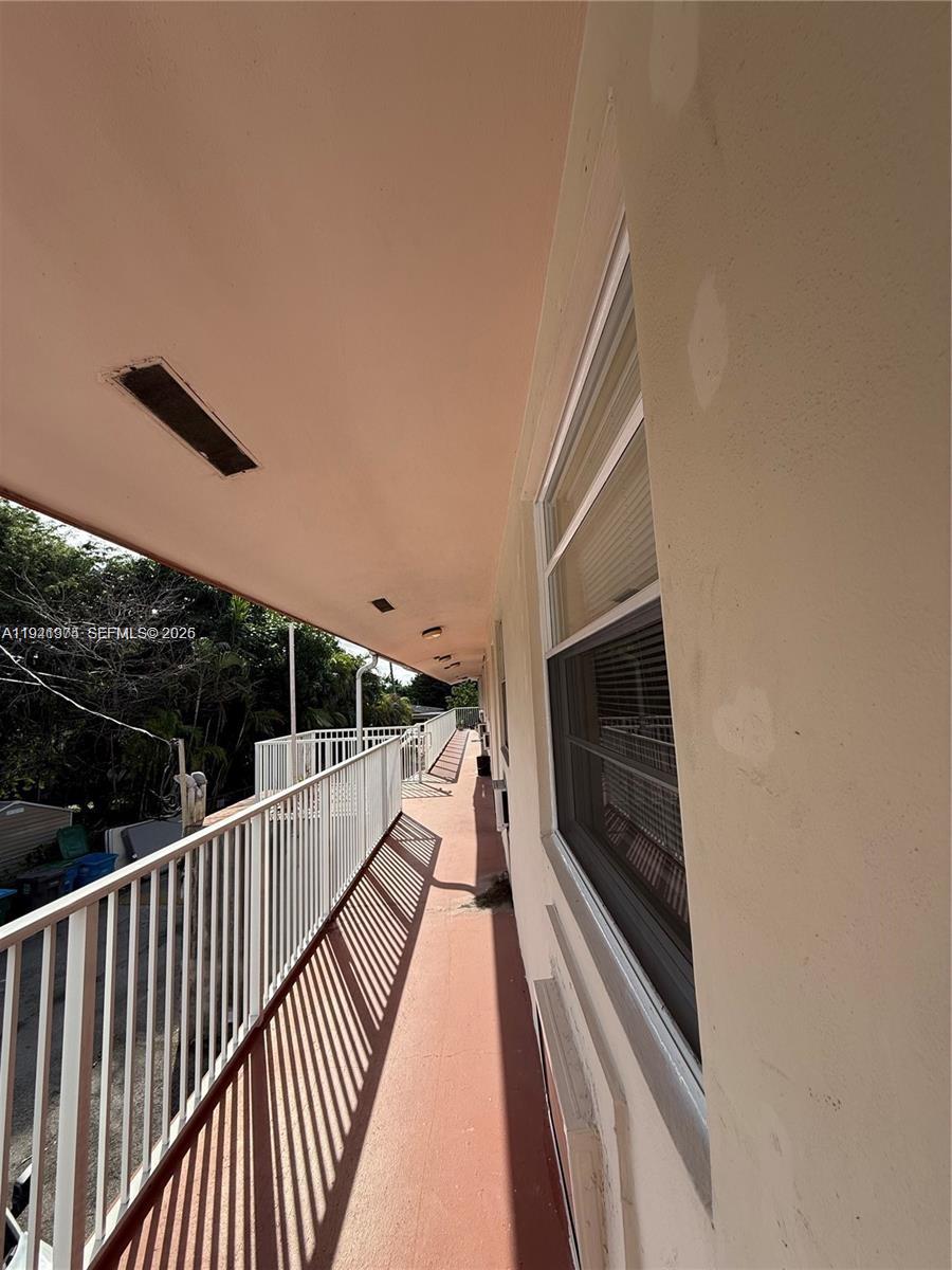 An exterior walkway with a white metal railing runs alongside a building with a window — 2915 Plunkett St # 12A, Hollywood FL 33020, HOLLYWOOD, FL