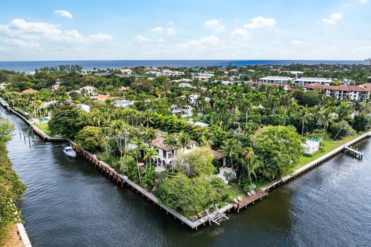 An aerial view of a waterfront house surrounded by lush trees and a wooden dock — 8 Driftwood Landing, Gulf Stream FL 33483, GULF STREAM, FL