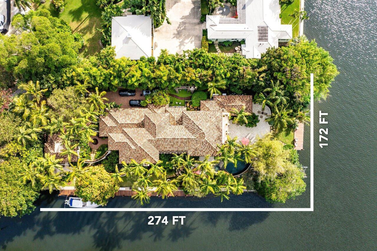 An aerial view shows a waterfront house with a tiled roof, pool, and boat dock — 8 Driftwood Landing, Gulf Stream FL 33483, GULF STREAM, FL
